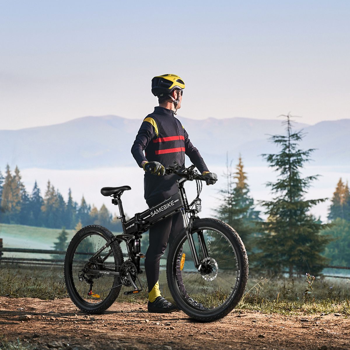Person steht neben einem schwarzen E-Bike. Trägt Helm und Sportkleidung. Landschaft im Hintergrund.