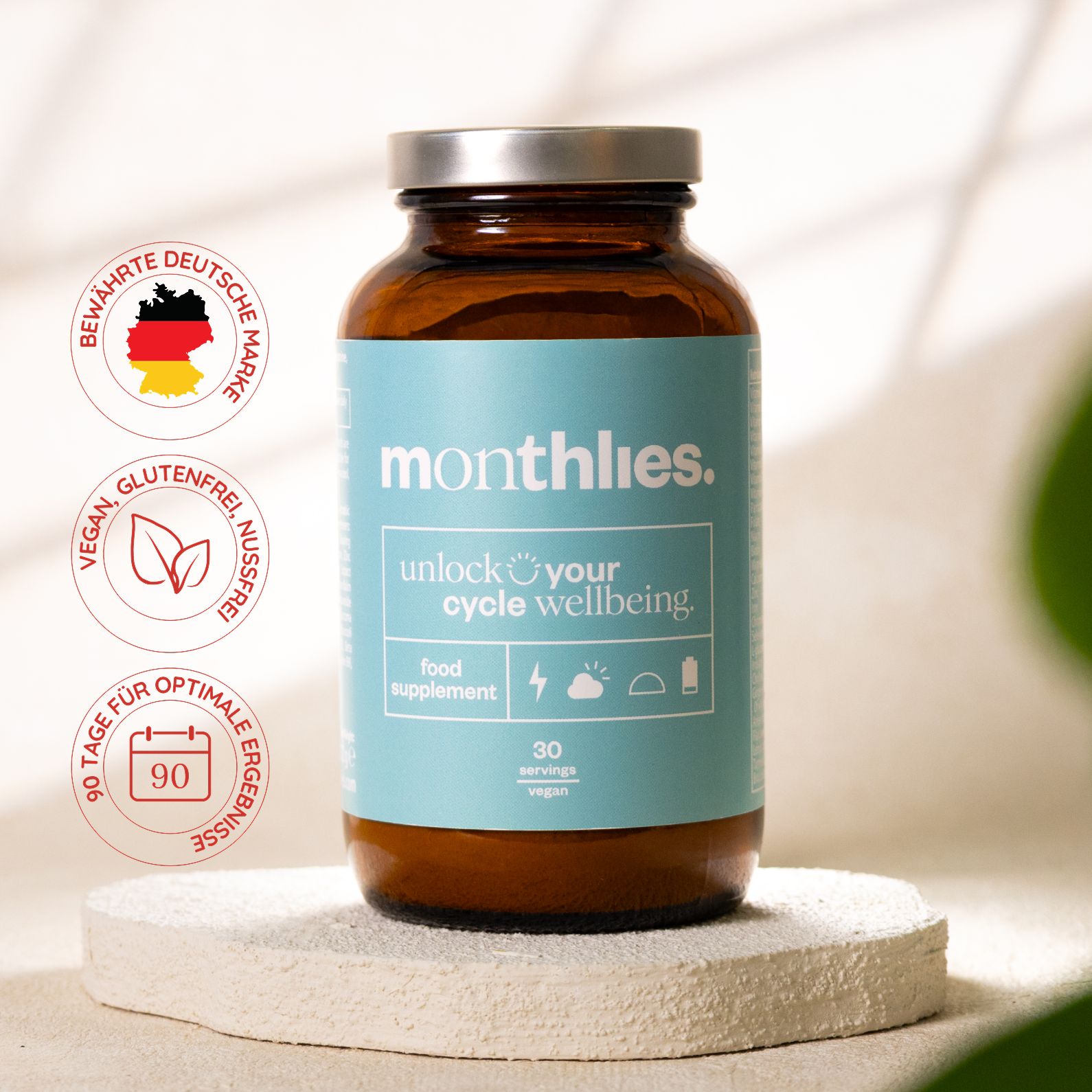 Braune Glasflasche mit blauem Etikett. Aufschrift: monthlies. unlock your cycle wellbeing. 30 servings. Vegan, glutenfrei, nussfrei. 90 Tage für optimale Ergebnisse.