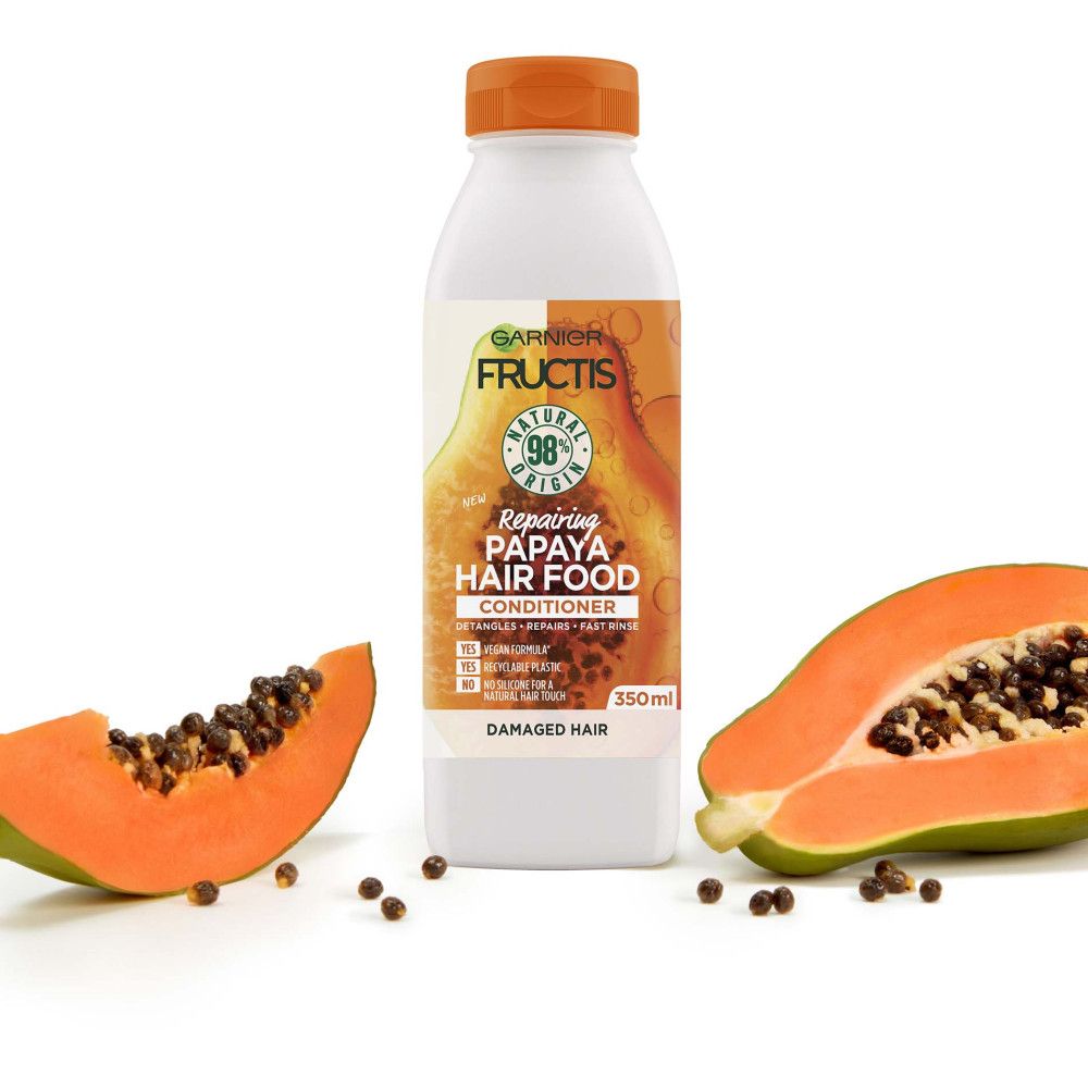 Fructis Papaya Hair Food Spülung. Flasche mit Papaya-Hälften und Samen. Produktinformationen auf dem Etikett.