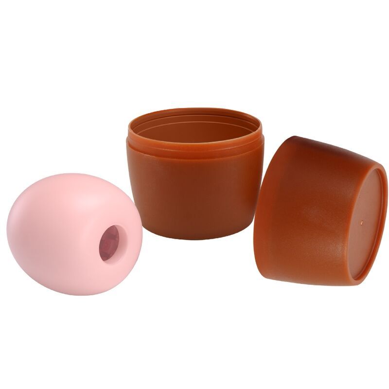 Rosa Ei mit Loch, neben geöffneter brauner Dose und Deckel. Nahaufnahme.