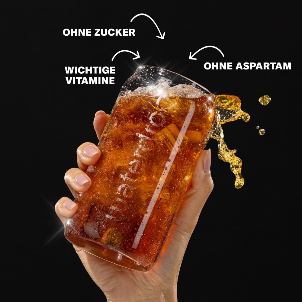 Glas mit Cola-Getränk. Hand hält Glas. Text: Ohne Zucker, wichtige Vitamine, ohne Aspartam. waterdrop® Logo sichtbar.