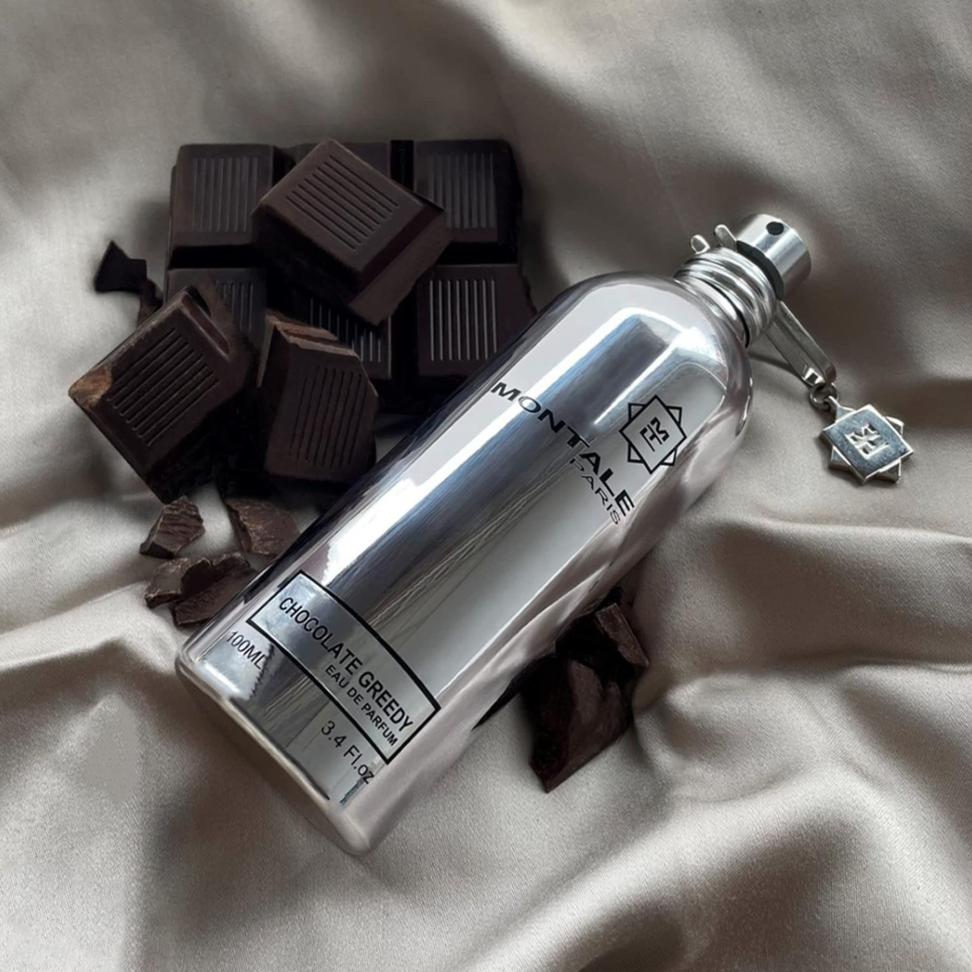 Montale Chocolate Greedy Eau de Parfum Spray neben Schokoladenstücken auf Stoff.