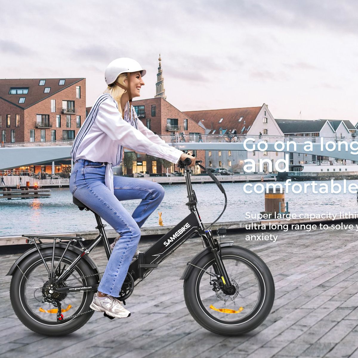 Person fährt auf einem E-Bike SAMEBIKE LOTDM200-II. Schwarzes Fahrrad, breite Reifen, Gepäckträger. Stadtlandschaft im Hintergrund.