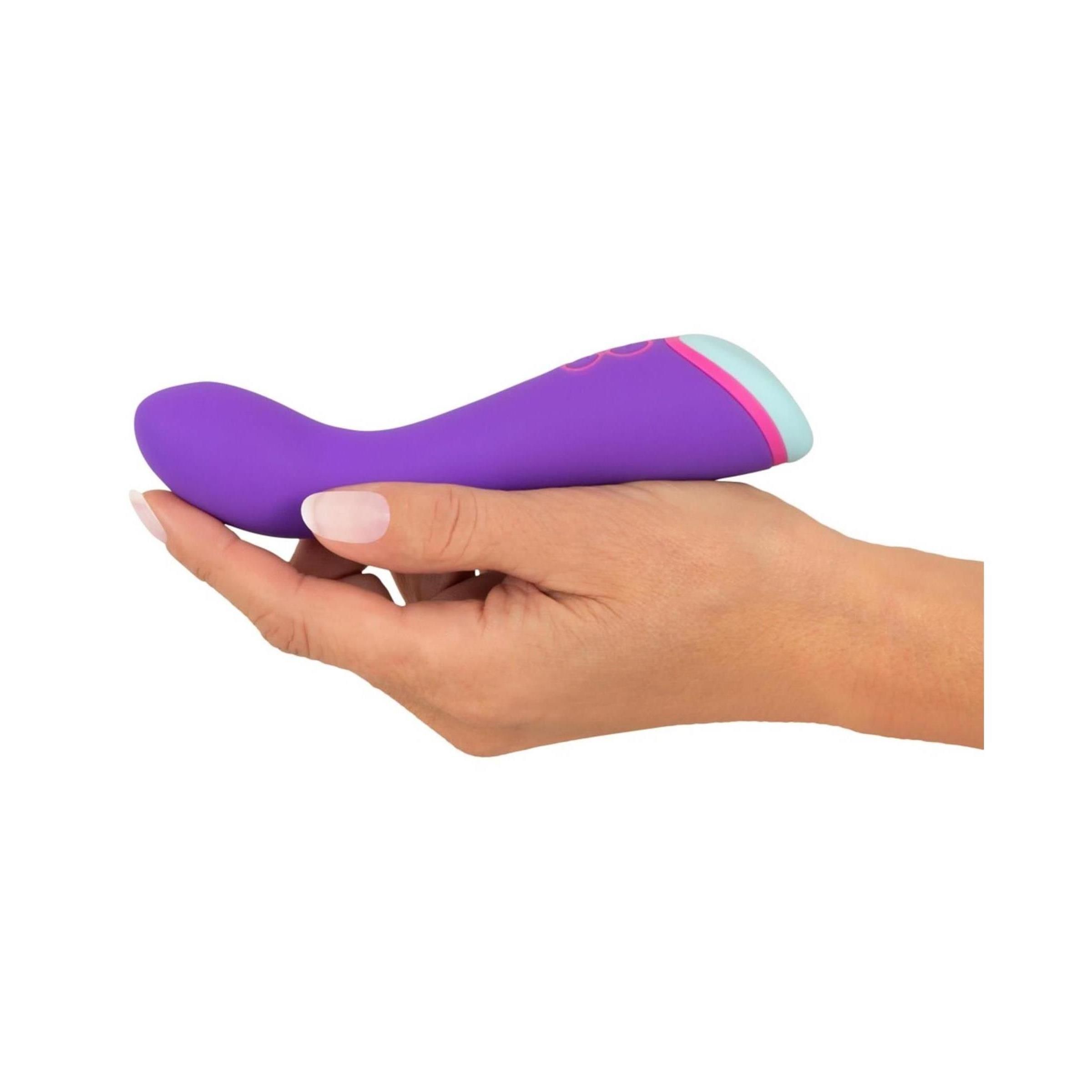 Lila Vibrator in einer Hand gehalten. Rosa und hellblauer Akzent am Ende.