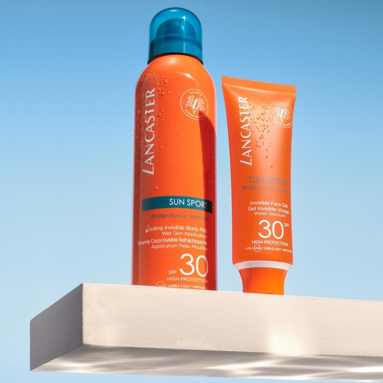 Zwei Produkte: Spray und Tube Lancaster Sun Sport SPF30. Auf weißer Oberfläche.