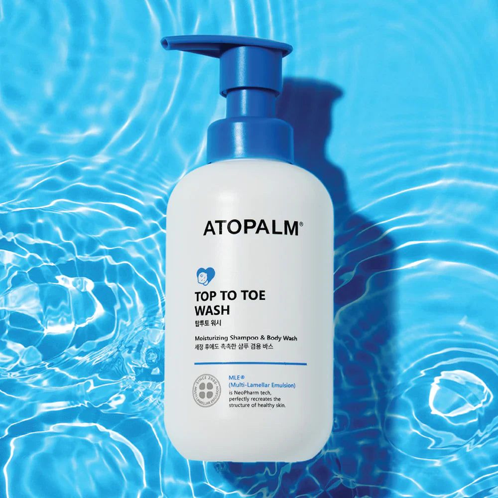 Weiße Flasche mit blauem Pumpkopf. Aufschrift: ATOPALM, TOP TO TOE WASH. Hintergrund: Wasser.