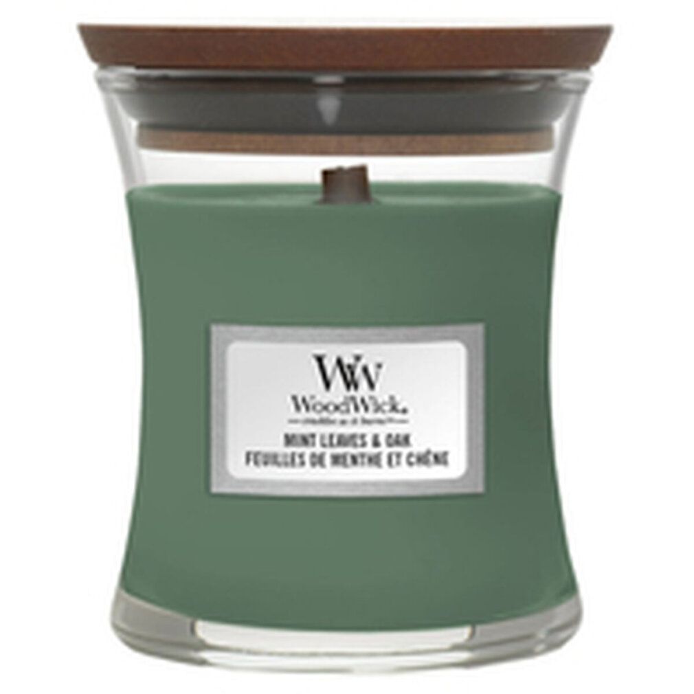 Grüne Kerze in Sanduhrform mit Holzdeckel. Aufkleber mit Produktnamen und Marke WoodWick. Mint Leaves & Oak.