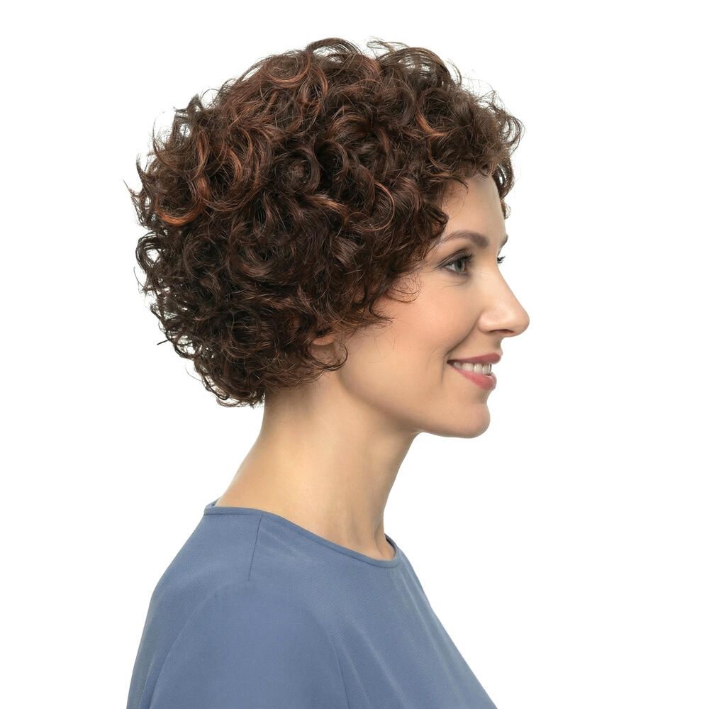 Frau mit brauner, lockiger Perücke. Seitenansicht. Sie trägt ein blaues Oberteil. Hintergrund weiß.