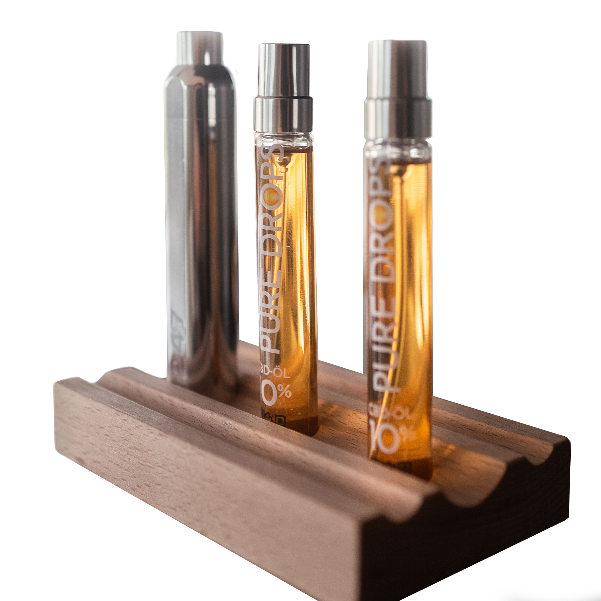 Due flaconi con liquido dorato, un flacone argento, su supporto in legno. Scritta: "PURE DROPS 10% CBD-ÖL".