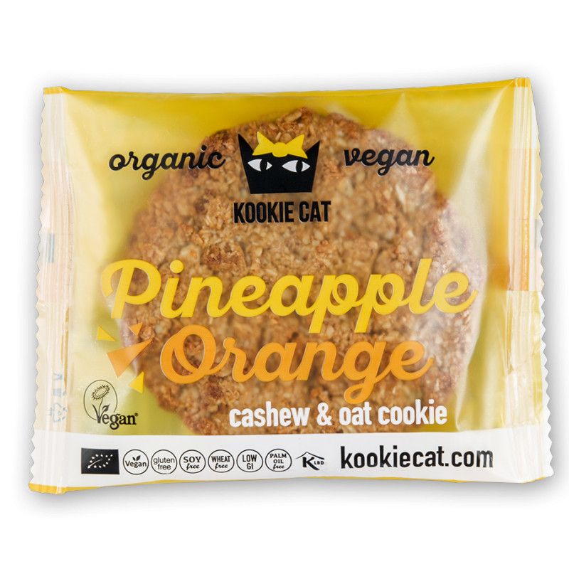 Kookie Cat-Keks in gelber Verpackung. Aufschrift: Pineapple Orange, Cashew & Oat Cookie. Vegan-Siegel.