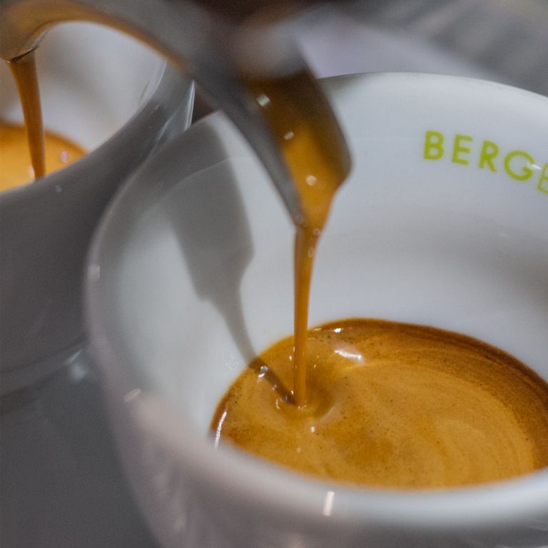 Espresso wird in eine weiße Tasse gegossen. Auf der Tasse steht BERGE.
