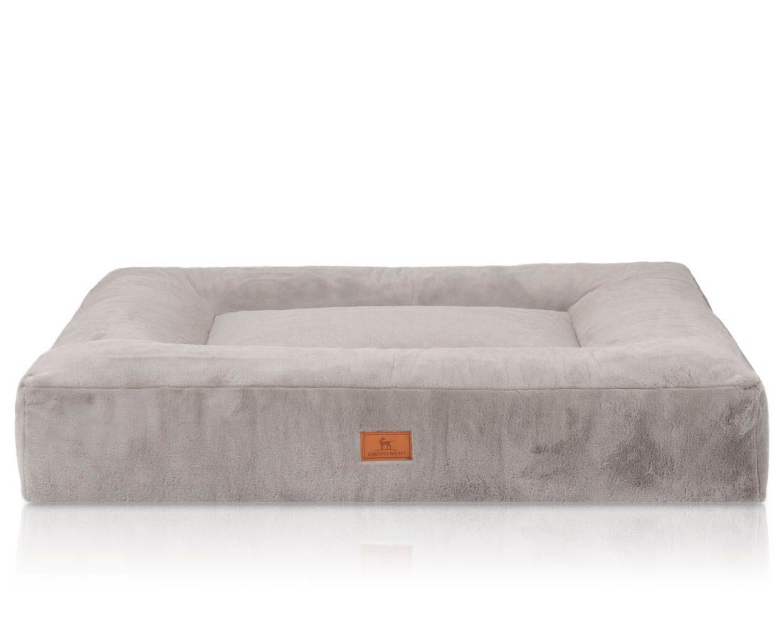 Orthopädisches Hundebett in Grau. Quadratische Form mit erhöhtem Rand. Kleines Markenlabel. Weiches Material.