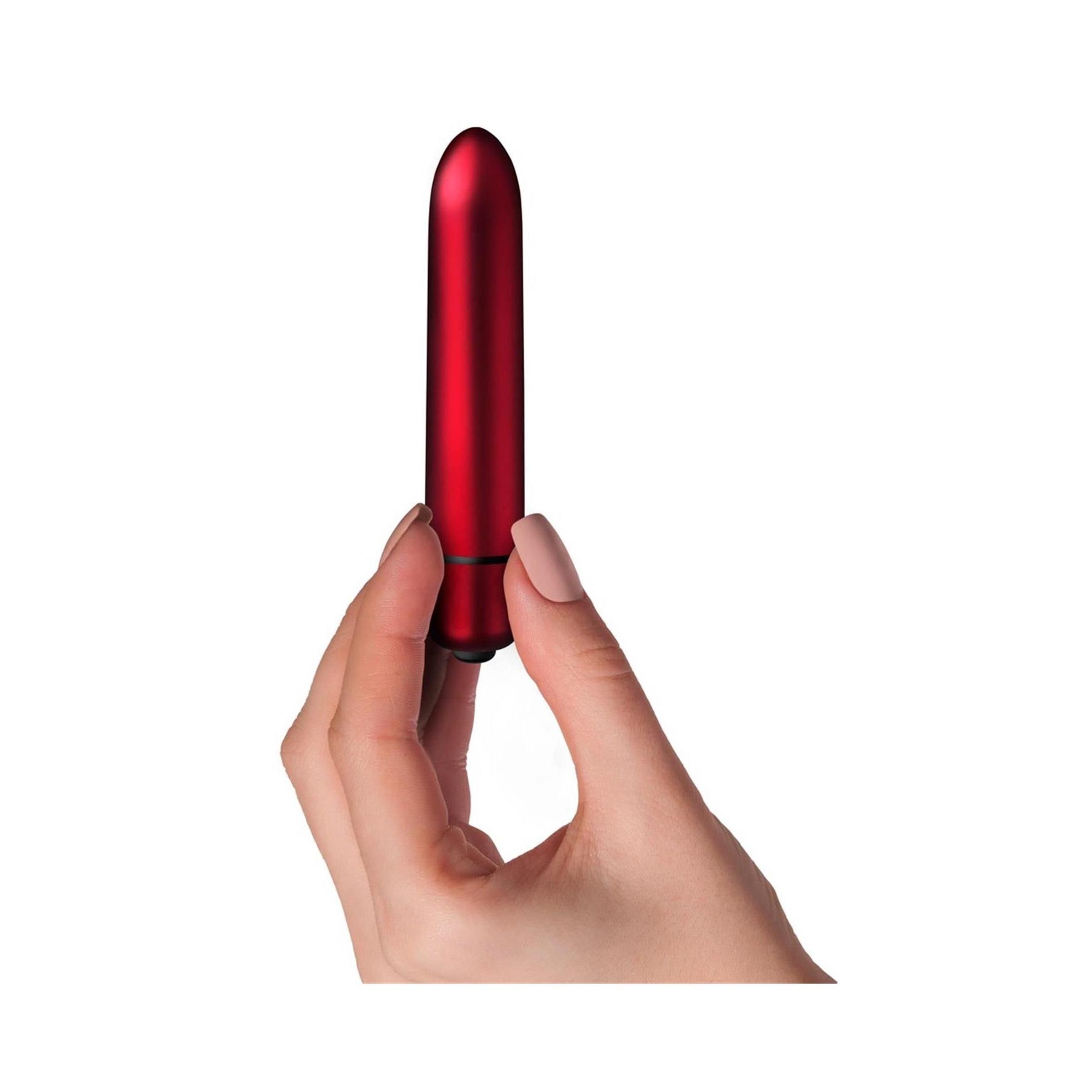 Roter Vibrator in Hand gehalten. Zylindrische Form, abgerundete Spitze. Schwarzer Ring am unteren Ende.