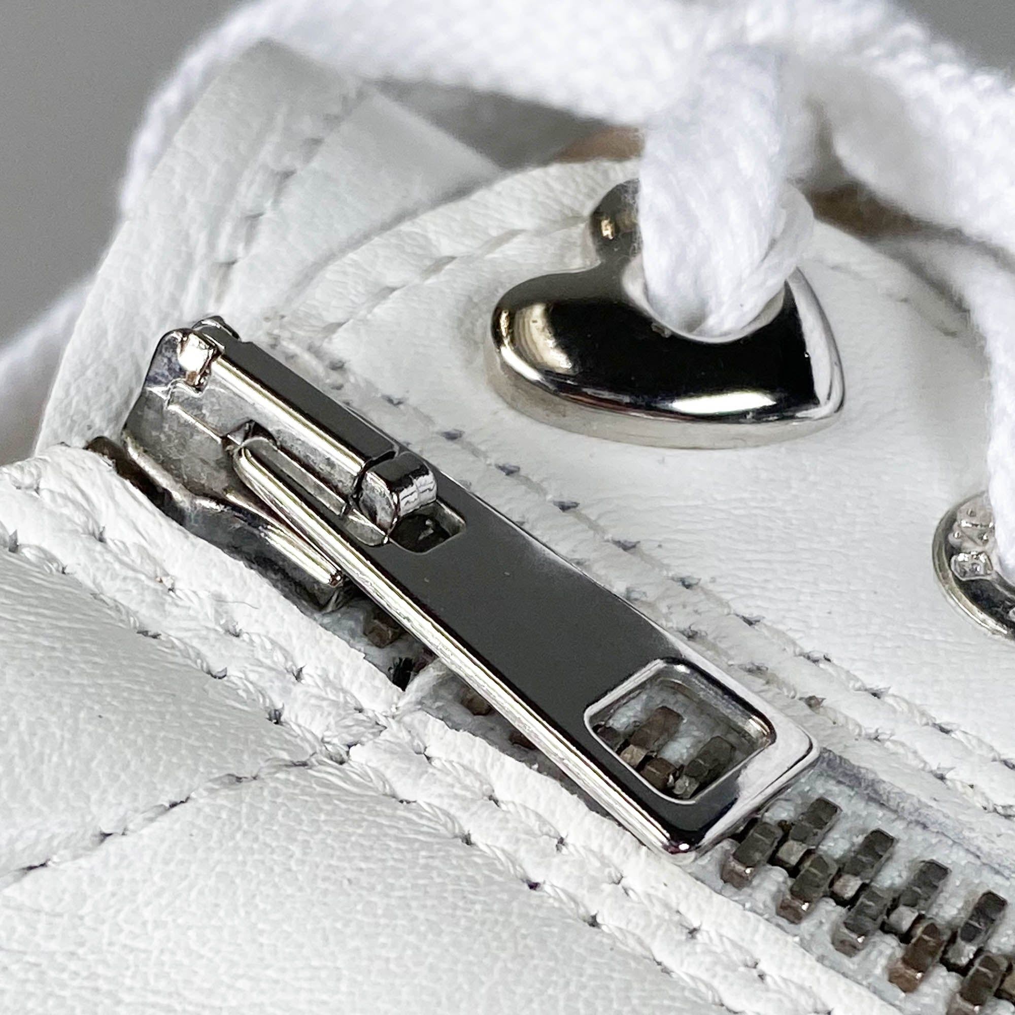 Detailansicht eines weißen Schuhs mit Reißverschluss. Reißverschluss aus Metall, weiße Schnürsenkel.