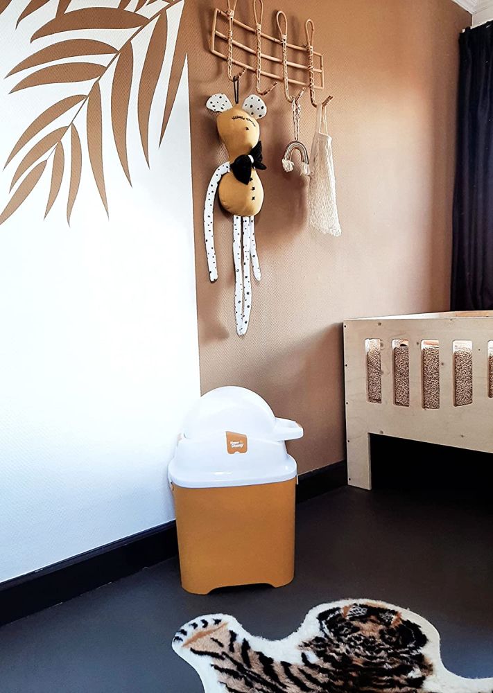 Gelber Windeleimer in einem Kinderzimmer. Weißer Deckel mit Ausguss. Aufschrift: Diaper Champ.