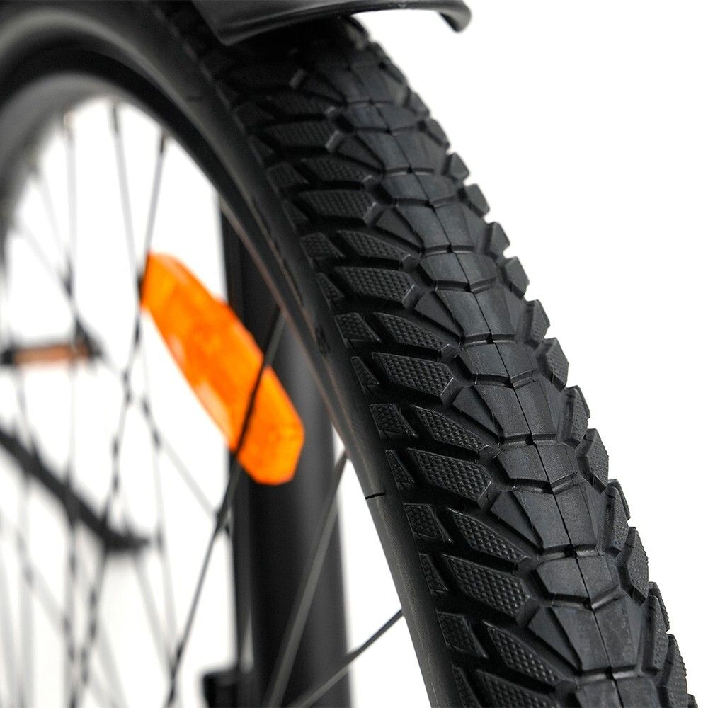 Nahaufnahme eines schwarzen Reifens mit Profil. Ein orangefarbener Reflektor ist sichtbar.