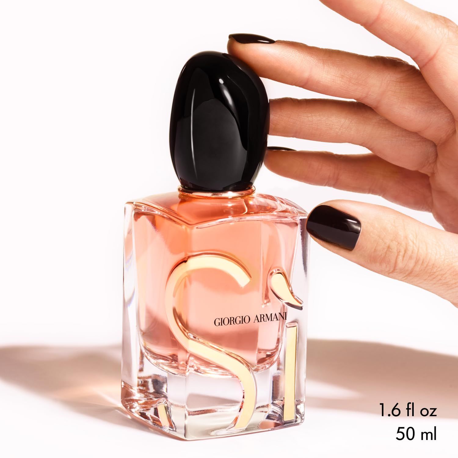 Giorgio Armani Si Eau de Parfum Intense Flakon. Goldene Buchstaben und Details. Schwarzer Deckel. Rosa Flüssigkeit. Hand.