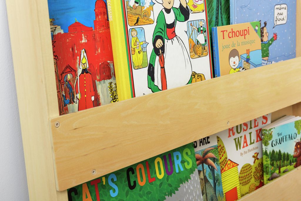 Nahaufnahme eines Bücherregals aus Holz mit Büchern. Sichtbar sind Buchrücken mit Titeln und Illustrationen.
