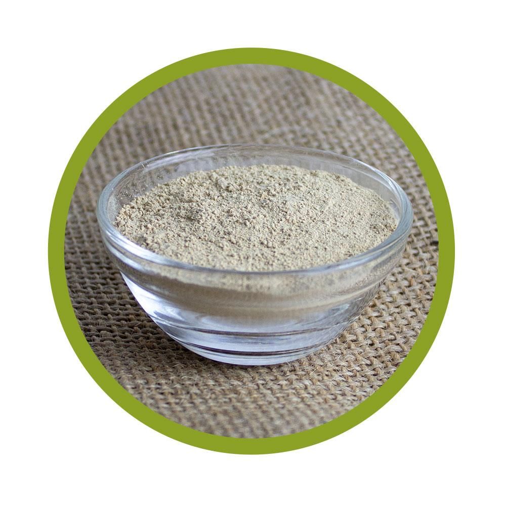 Glaschale mit Pulver, umrandet von grünem Kreis. Auf grobem Untergrund.