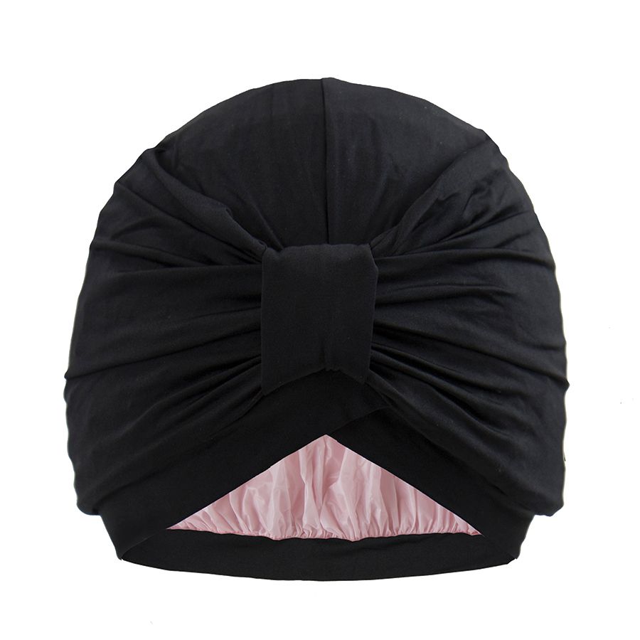 Un cappello per la doccia STYLEDRY nero, modello "After Dark", con interno rosa. Il cappello ha una forma a turbante con un nodo decorativo sul davanti. Il materiale sembra morbido e flessibile.