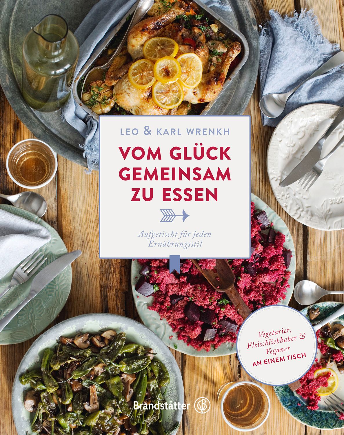Buchcover mit Titel "Vom Glück gemeinsam zu essen". Aufgetischt für jeden Ernährungsstil. Auf einem Holztisch mit Essen und Tellern.
