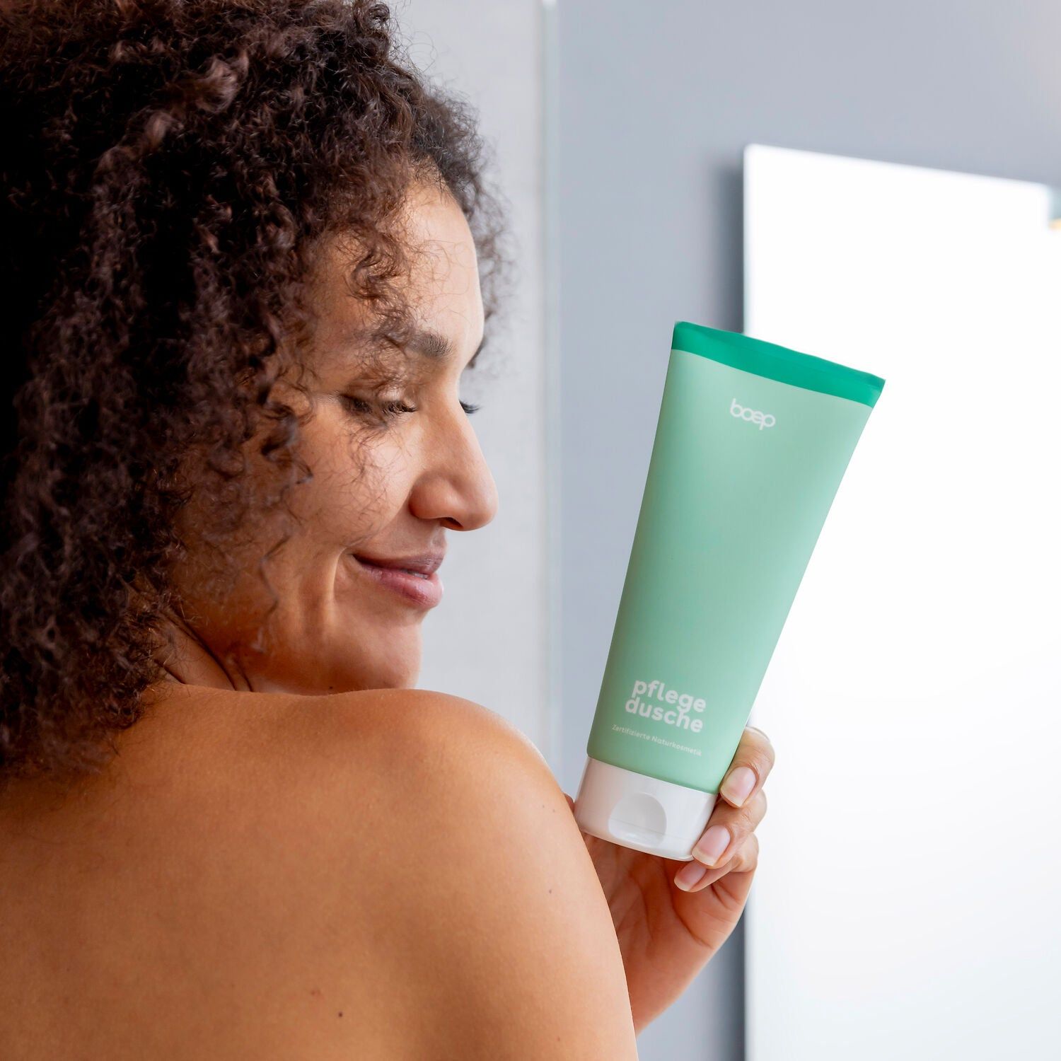 Eine Frau hält eine mintgrüne Tube 'boep pflegedusche' in der Hand.