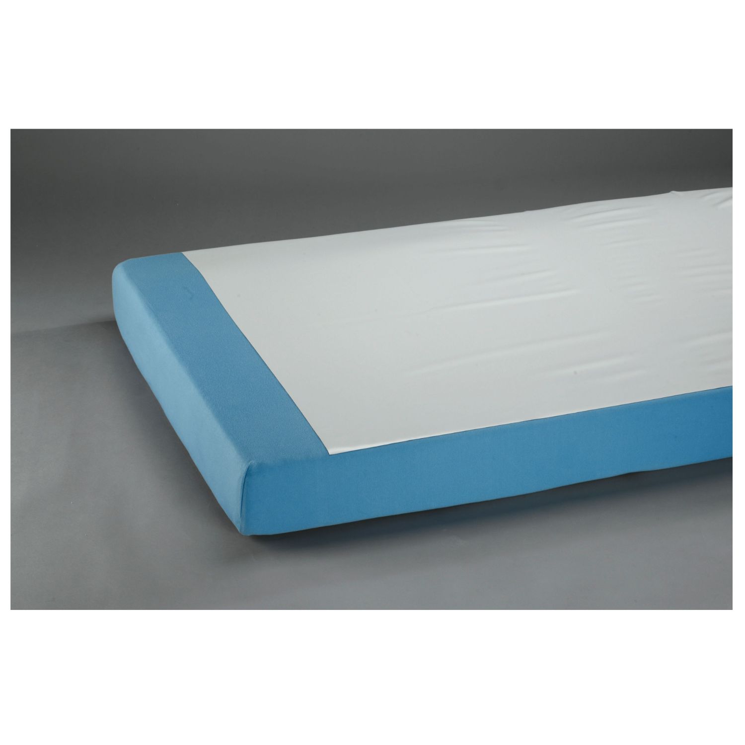 Bettauflage, weiß, auf blauem Bett. PVC-Material. Eckansicht, grauer Hintergrund.