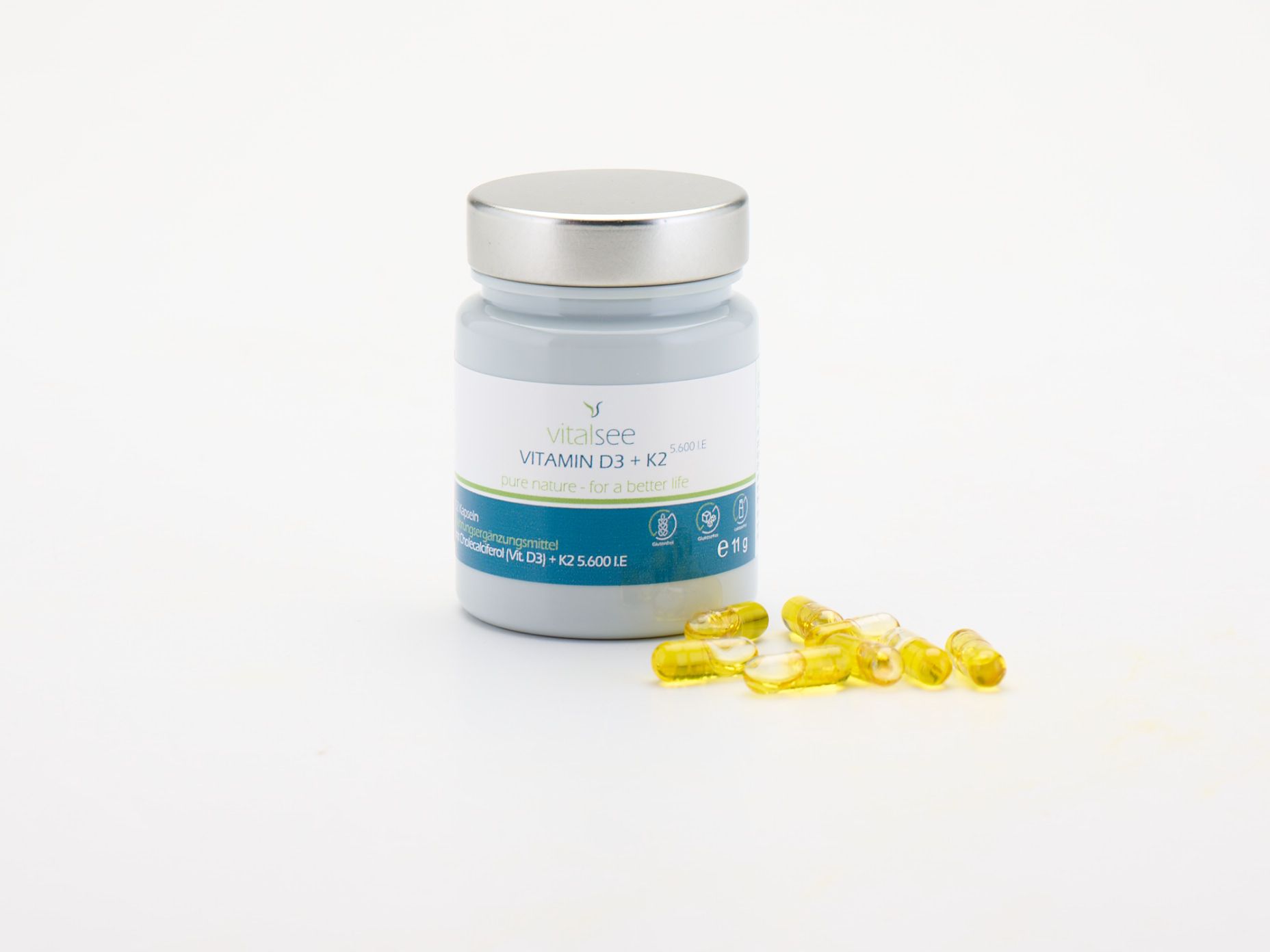 Graue Flasche mit silbernem Deckel und Kapseln daneben. Etikett "Vitalsee VITAMIN D3 + K2".