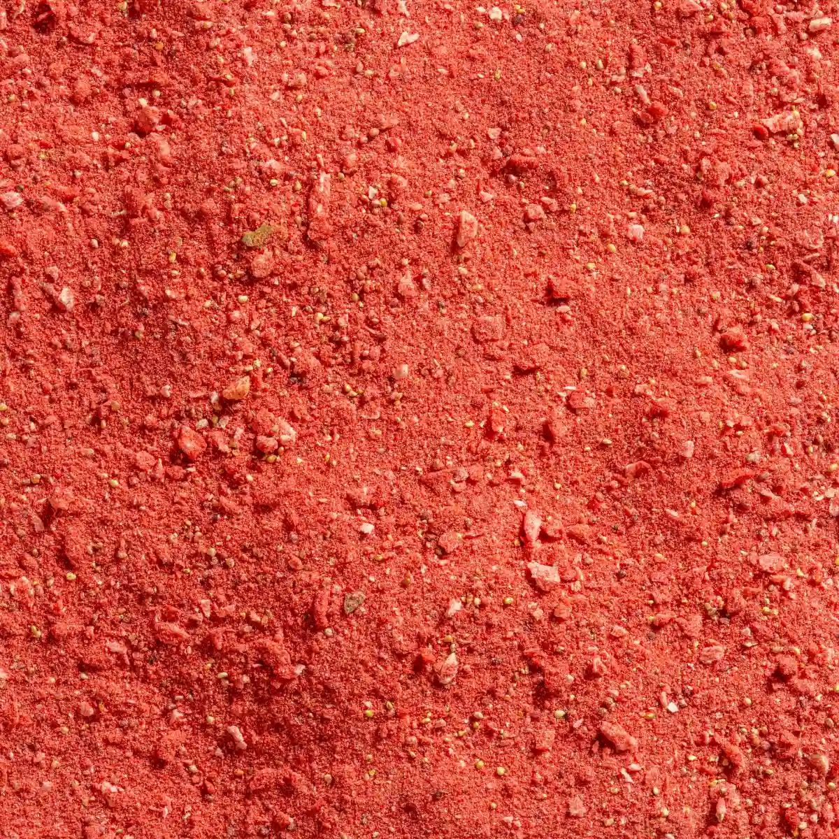 Nahaufnahme von Erdbeerpulver. Rote, feine Pulverstruktur mit kleinen Partikeln.