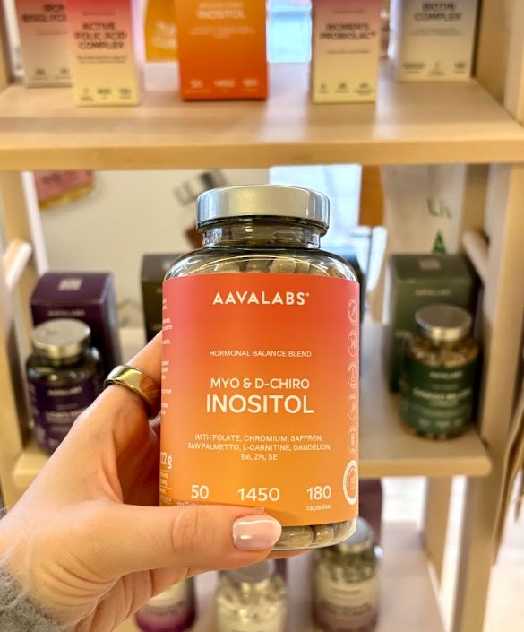 Hand hält eine Flasche Aavalabs Myo- & D-Chiro Inositol in einem Regal.