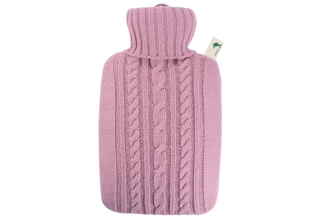 Wärmflasche mit Strickbezug in Pastellrosa. Mit Zopfmuster und Rollkragen. Anhänger mit Logo.