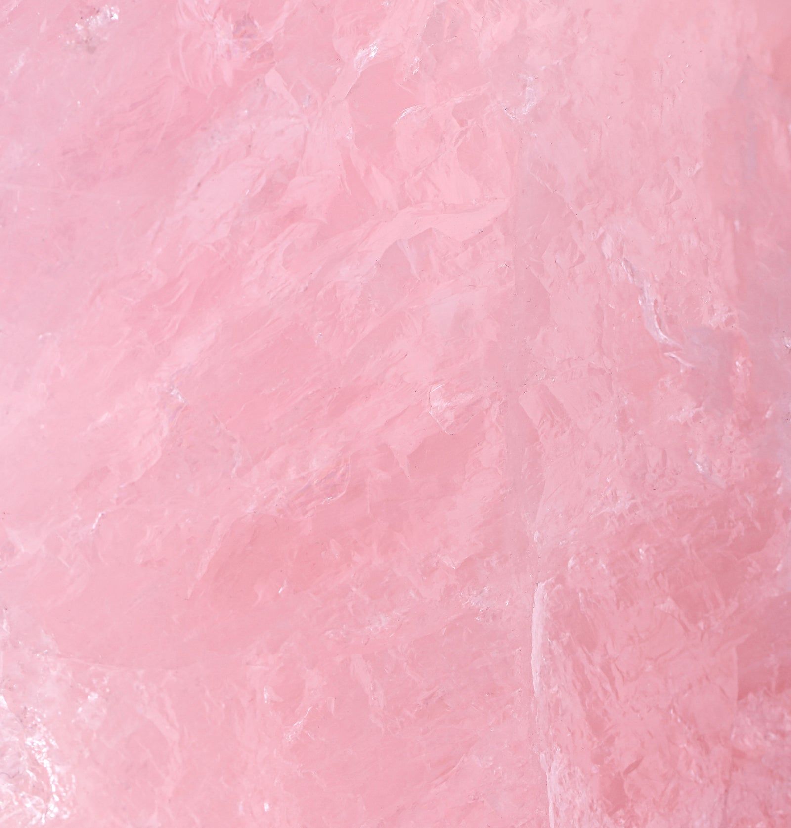 Nahaufnahme von rosa Rosenquarz. Unregelmäßige Oberfläche, helle Farbe. Textur sichtbar.