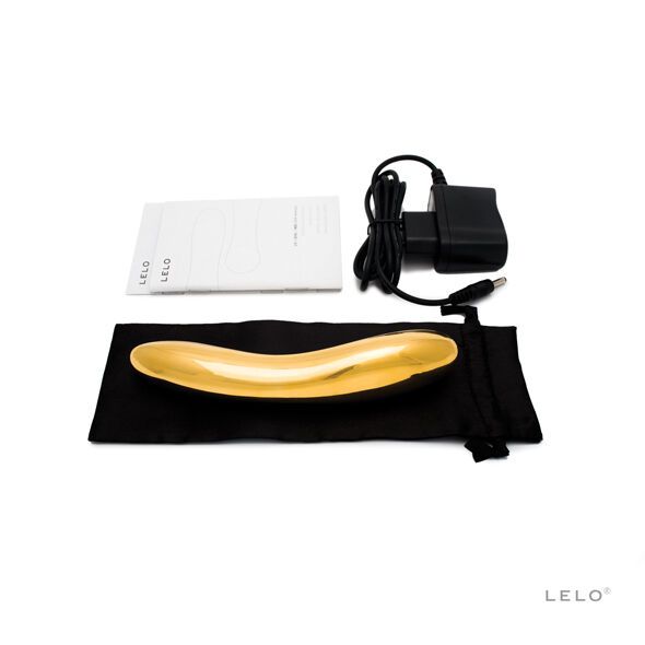 Goldfarbener Vibrator, Ladekabel, Netzteil und Anleitung. Schwarze Tasche. LELO-Logo.
