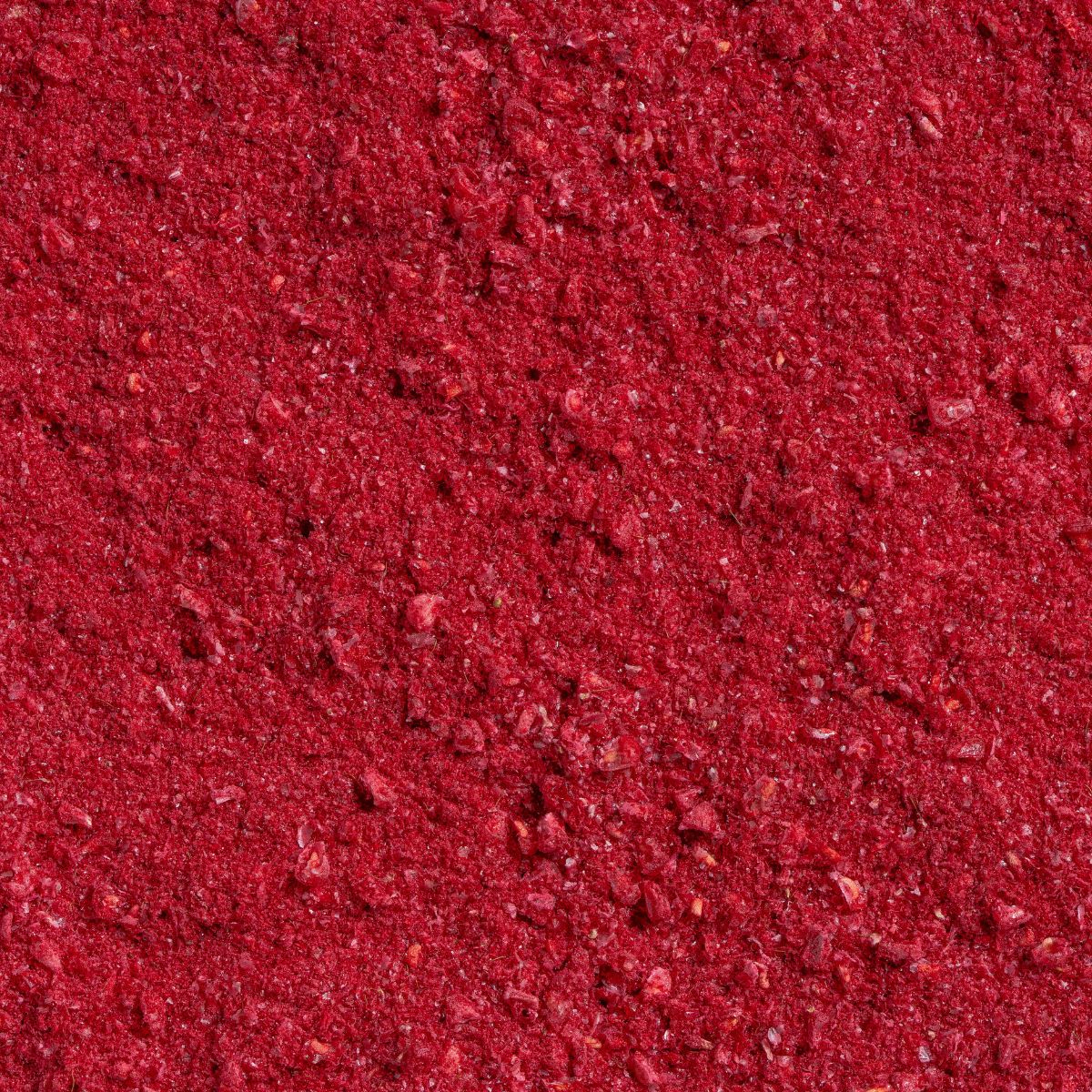 Nahaufnahme von gefriergetrocknetem Himbeerpulver. Rote Farbe, körnige Textur.