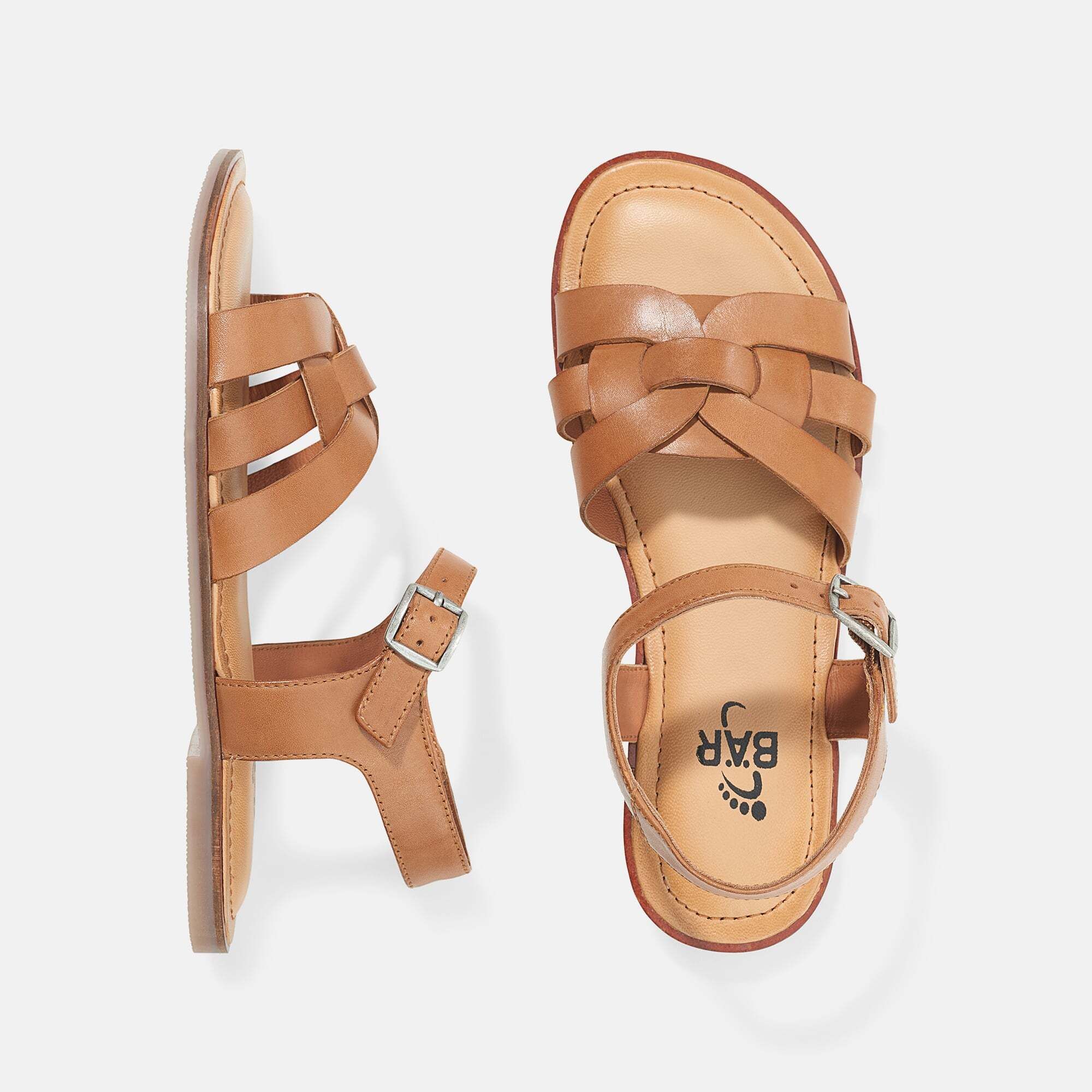 Zwei braune Sandalen mit geflochtenem Riemen und Schnalle. Flache Sohle. Draufsicht.