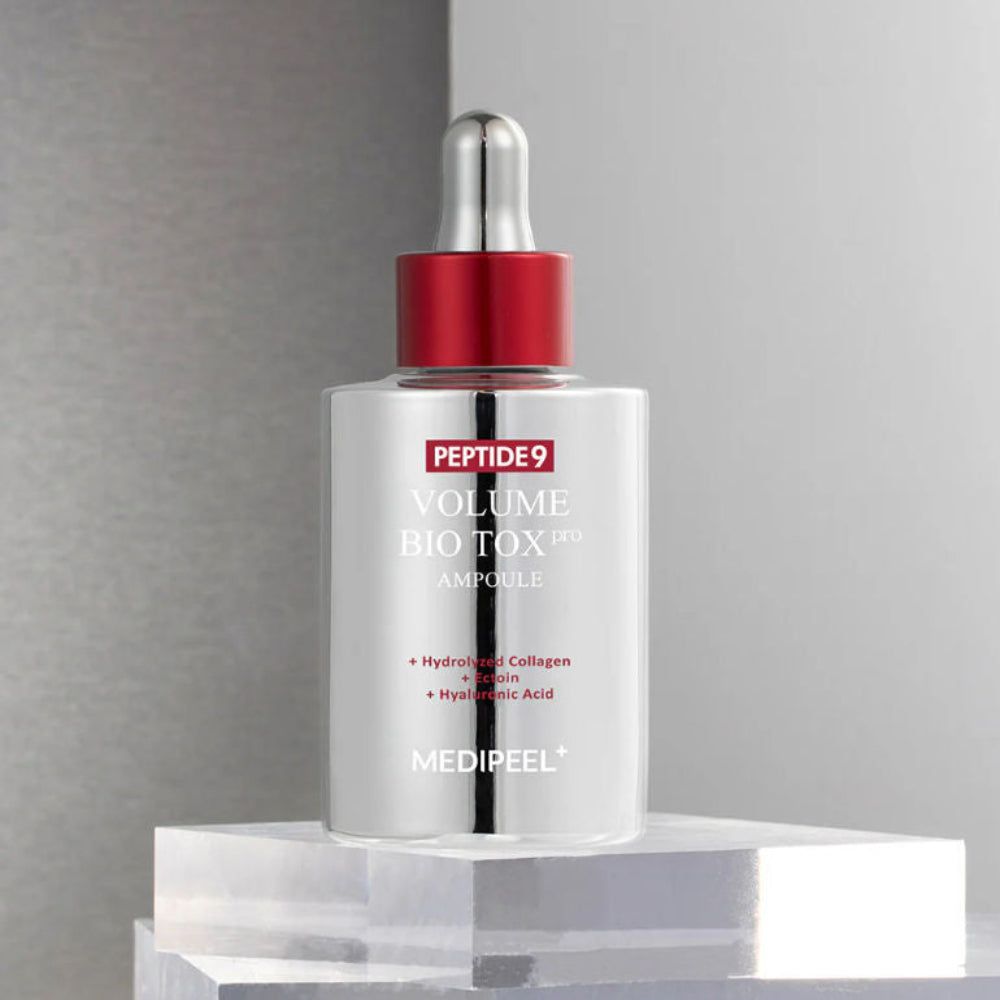 Silberne Flasche mit rotem Verschluss und Pipette. Aufschrift: Peptide 9 Volume Bio Tox Ampoule. Marke Medipeel. Auf transparentem Podest.