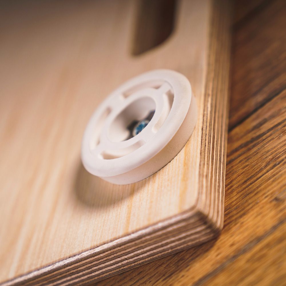 Nahaufnahme eines weißen Rades an der Movebox aus Holz. Das Rad ist an der Seite der Box befestigt.