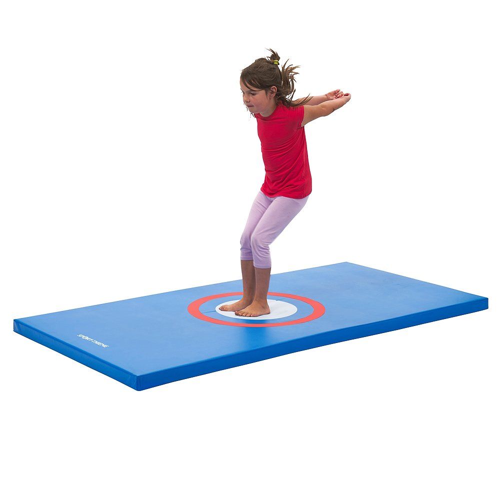 Blaue Turnmatte mit rotem und weißem Zielkreis. Ein Mädchen springt auf der Matte.