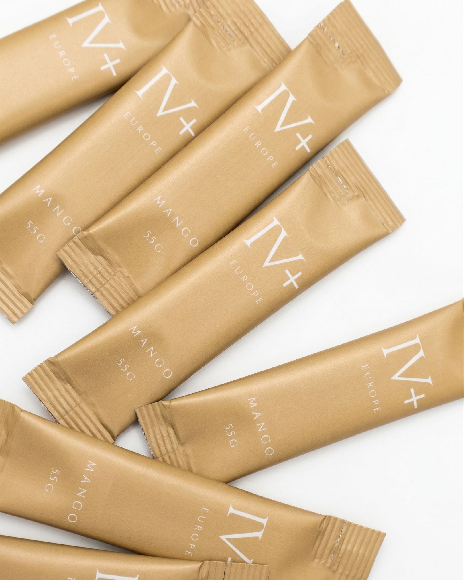 Mehrere goldfarbene Beutel mit der Aufschrift IV+ EUROPE MANGO liegen auf weißem Untergrund.