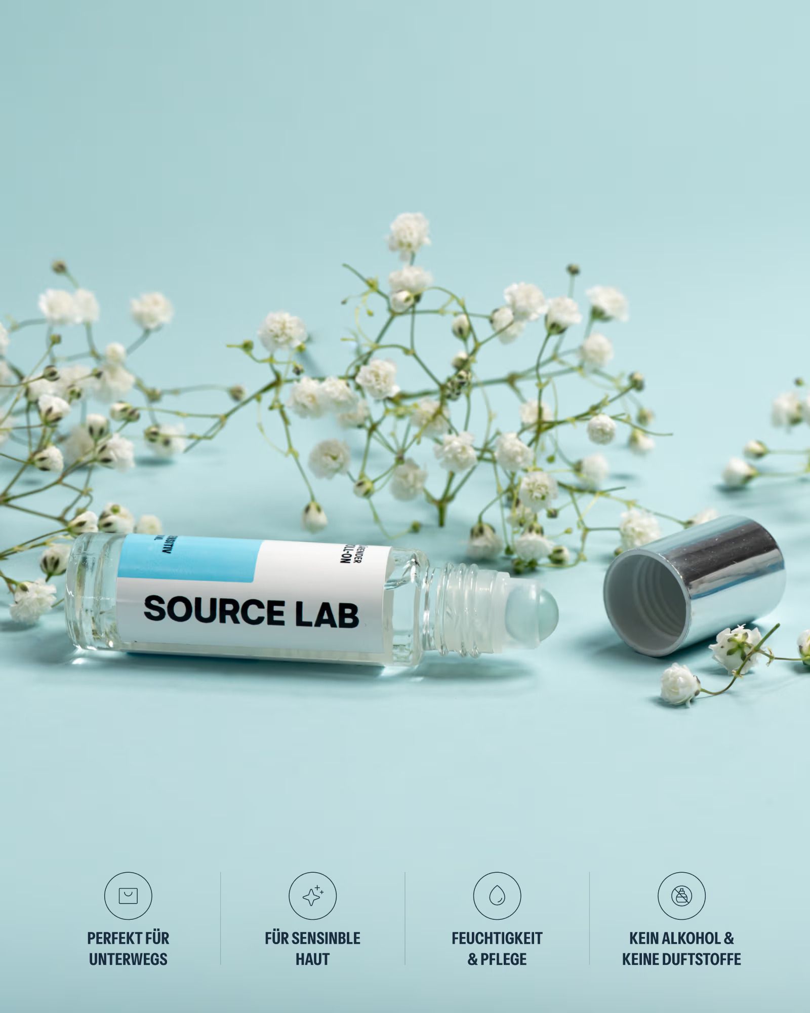 Source Lab klärender Roll-On mit geöffnetem Deckel, liegend auf blauem Hintergrund mit weißen Blüten. 10 ml.