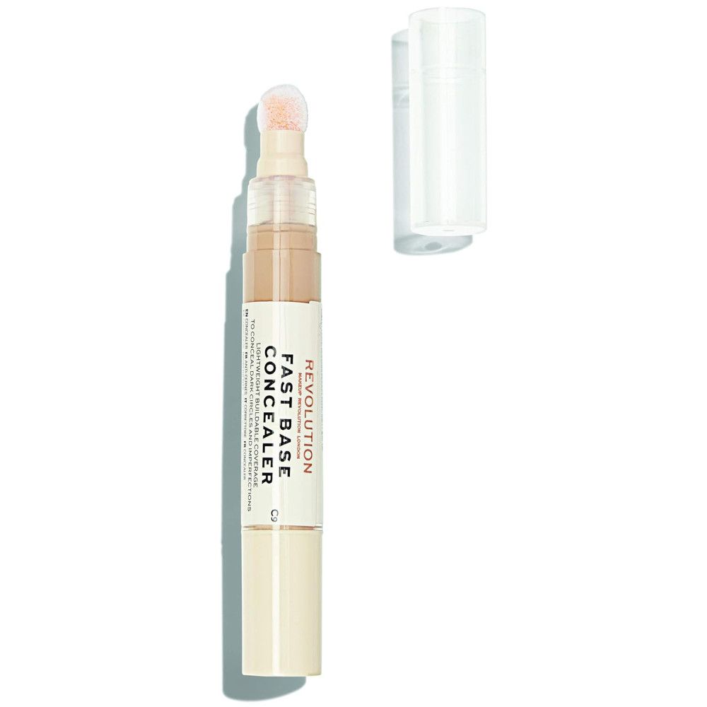 Makeup Revolution Fast Base Concealer. Beige Farbton, Stiftform mit Applikator. Kappe daneben. Produktname und Marke sichtbar.