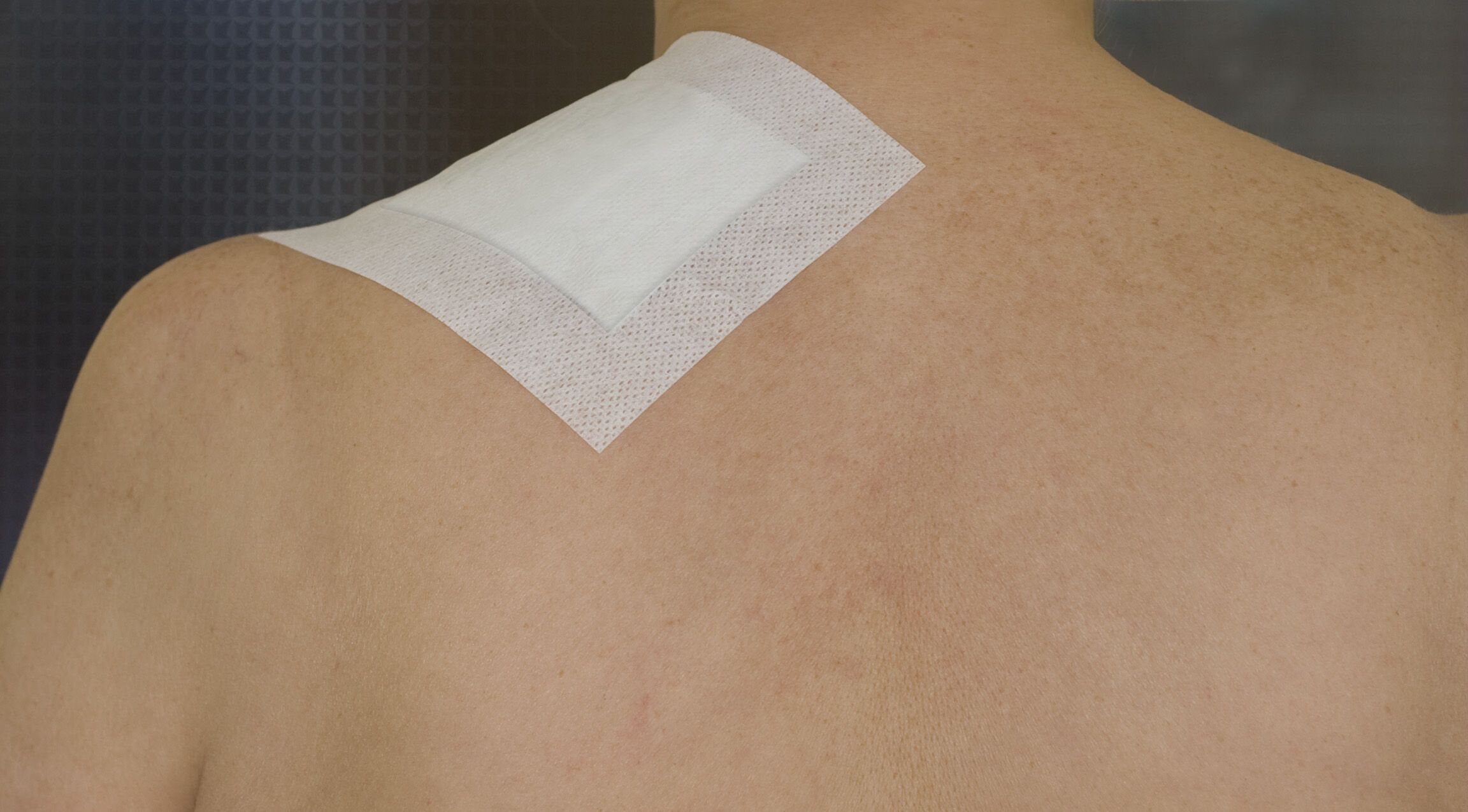 Quadratisches Pflaster auf Schulter. Weißes, rechteckiges Pad auf weißem, quadratischem Träger.