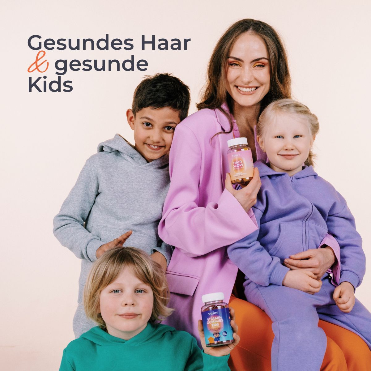 Eine Frau und drei Kinder halten Flaschen mit Vitamin-Gummis. Aufschrift: yuicy. Hintergrund: hell.