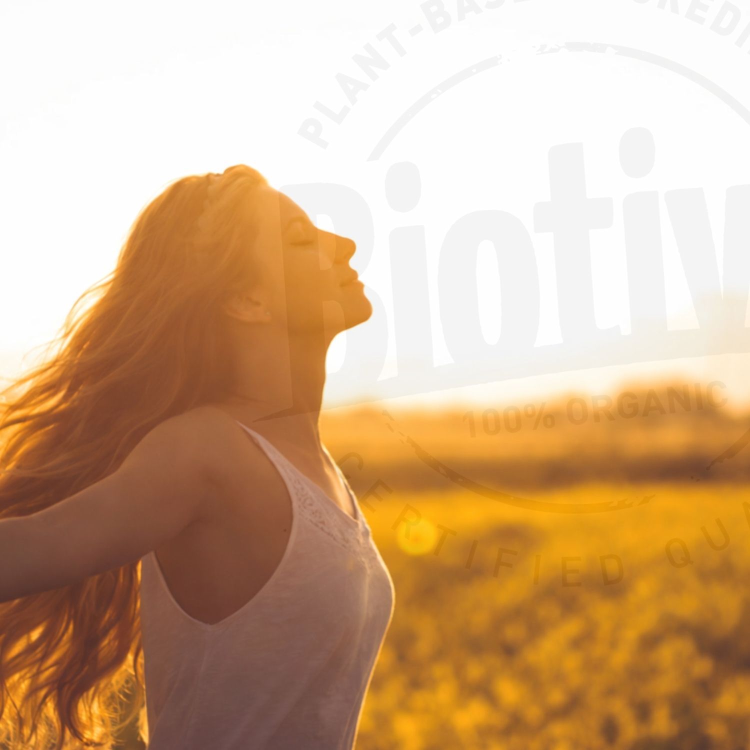 Frau mit offenen Armen im Sonnenlicht. Text: Biotiva, 100% Organic, Certified Quality. Hintergrund: gelbes Feld, blauer Himmel.