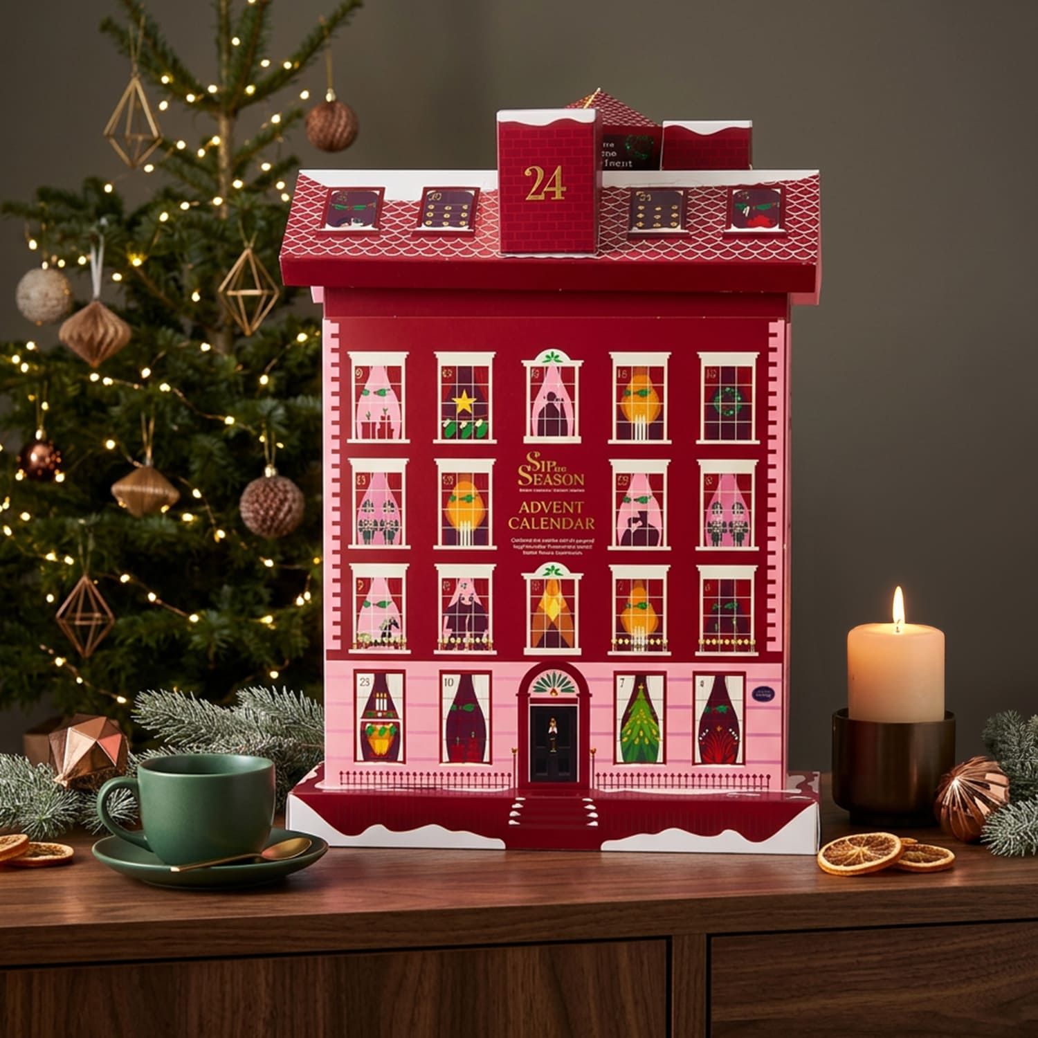 Adventskalender in Hausform neben Weihnachtsbaum, Tasse und Kerze. Festliche Dekoration.