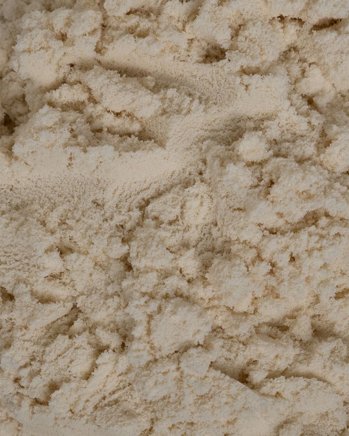 Nahaufnahme von hellem, beige Pulver. Feine Textur, leicht körnig.