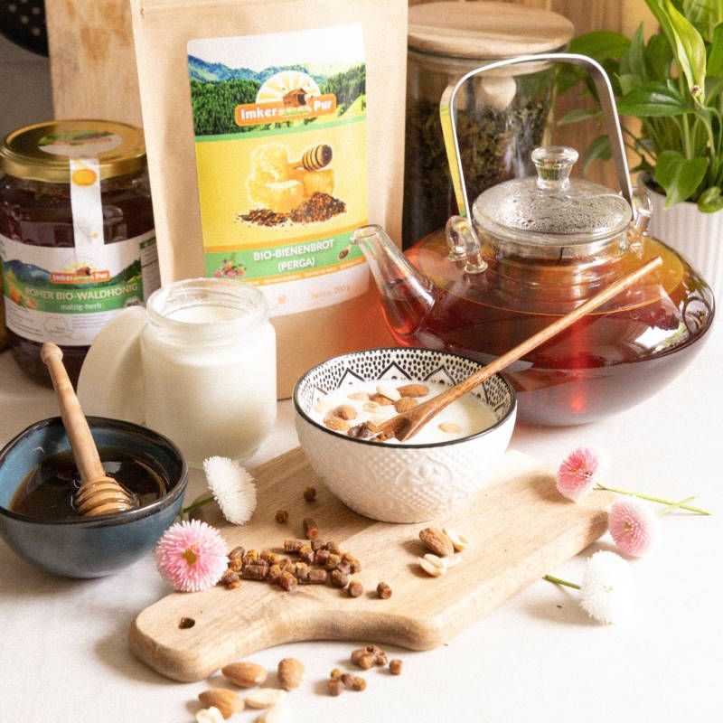 Verschiedene Lebensmittel auf einem Tisch. ImkerPur Bio-Bienenbrot, Honig, Milch, Tee, Mandeln und Blüten.