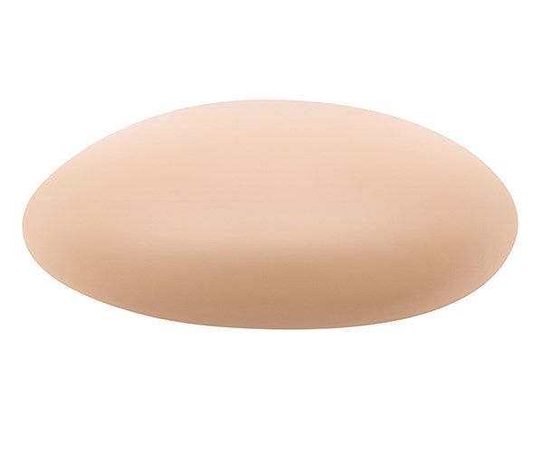 Brustprothese in Ellipsenform, hautfarben. Material und Formgebung sind erkennbar.