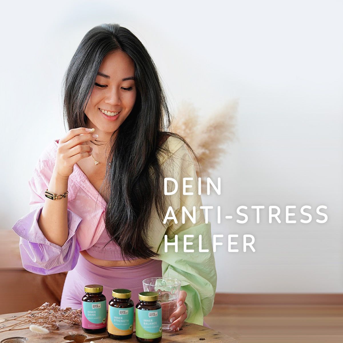 Frau mit drei Flaschen Nahrungsergänzungsmittel auf einem Tisch. Text: DEIN ANTI-STRESS HELFER.