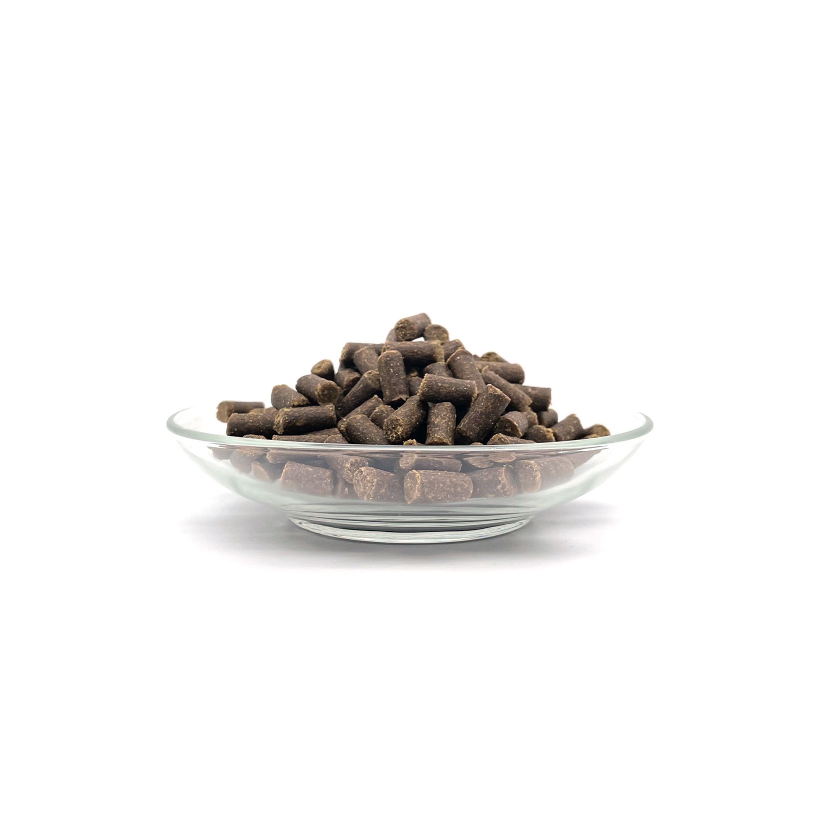 Haufenförmige, braune, stäbchenförmige Snacks in einer durchsichtigen Glasschale. Auf weißem Hintergrund.
